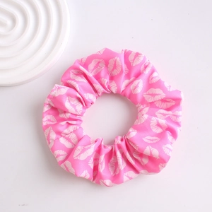 Close-up of pink scrunchie with white lip pattern against a clean white background