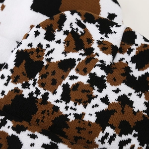 Macro texture of tricolor cow print knitted fabric with dense brown and black weaving