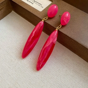 Detailed macro shot of pink marble acrylic drop earrings with elegant gold link accents