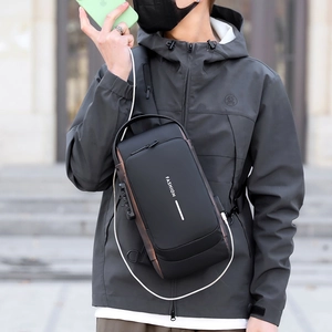 Black anti-theft sling bag with USB port and white FASHION lettering worn by a model