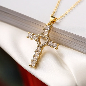 Détail macro d'un collier pendentif croix dorée avec cœur évidé et oxydes de zirconium