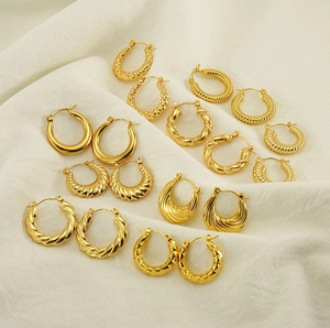 Detailed flat lay of diverse 18K gold-plated twisted hoop earrings on white linen