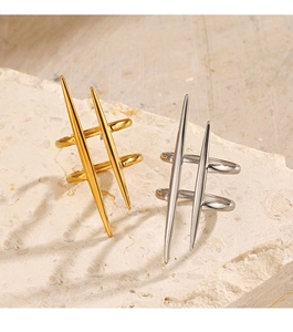 Detail of gold and silver spiked double-row rings on a textured beige stone surface