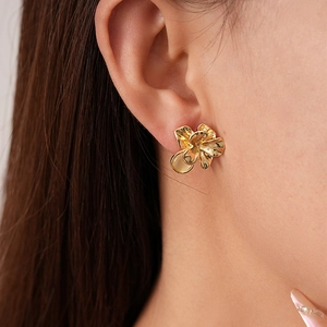 Nahaufnahme der goldenen Blumenohrringe mit Harzstein an einem Model im Vintage-Stil