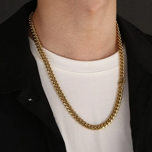 Close-up of a thick gold stainless steel Cuban chain necklace worn by a male model