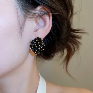 Elegant black cluster crystal stud earrings with gold accents on female model