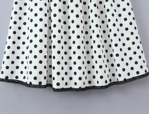 Detailed view of white polka dot dress hem with delicate black lace trim detailing