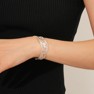 Macro detail of silver-colored hollow mesh bracelet showing intricate geometric textures