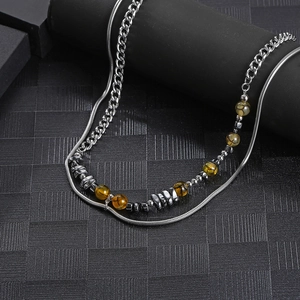 Double-layered necklace with silver snake chain and yellow stone beads on black background