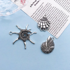 Close-up of antique silver ocean charms featuring a scallop shell and sea star