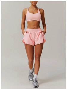 Brassière de sport rose à dos croisé et short ample assorti porté par un mannequin