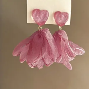 Detailed macro view of pink heart resin stud with delicate fabric flower tassel