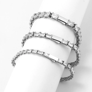Close-up of three silver tennis bracelets with square zircons on a white cylinder stand