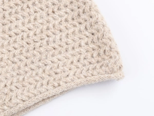 Macro shot of chunky beige knit fabric showing wool texture and detailed stitching
