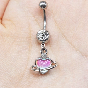 Macro shot of silver heart belly button ring with pink iridescent stone on palm