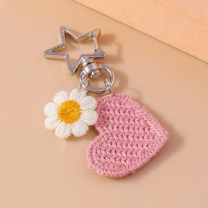 Charming knitted heart and daisy flower keychain with silver star clasp on beige surface