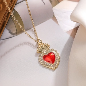 Gold plated heart pendant necklace with red gemstone and crown detail on vintage background