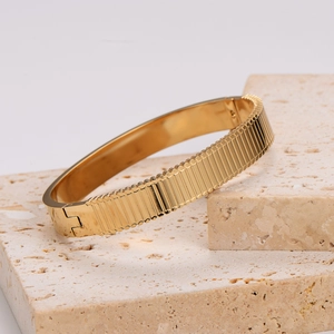 Gold stainless steel bangle with vertical striped texture and side hinge clasp closure