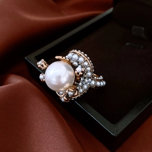 Detail of vintage pearl flower ring resting on a black jewelry box with brown silk background