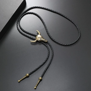 Detail of vintage bronze bull skull bolo tie with black braided cord and textured metal tips
