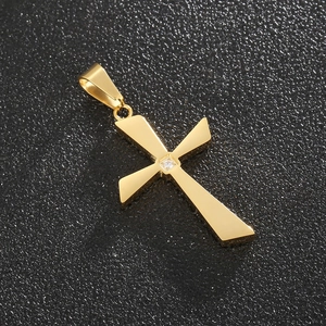 Macro shot of gold cross pendant with white crystal inlay on a dark textured background