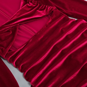 Détail d'une robe en velours bordeaux avec texture plissée et découpe élégante
