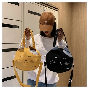 Detail of yellow and black cat-shaped canvas shoulder bags with 3D ears and embroidery