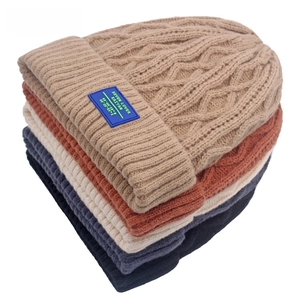 Stapel grof gebreide wollen mutsen in diverse kleuren met vintage kabelpatroon