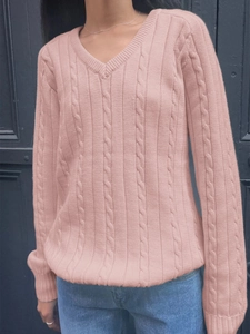 Detail of pink V-neck cable knit sweater texture and long sleeves on a model