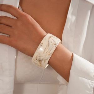 Close-up of wide marbled resin geometric bangle with brown and white stone patterns