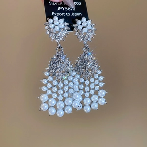 Macro detail of silver drop earrings with white pearls and sparkling rhinestones