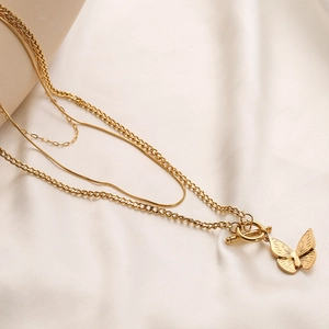 Multilayer gold stainless steel necklace with butterfly pendant and OT clasp on silk background