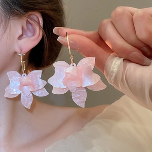 Gros plan sur de grandes boucles d'oreilles fleurs roses en résine nacrée élégante