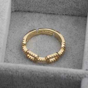 Close-up of golden hollow chain ring with pink zircons in a grey jewelry box