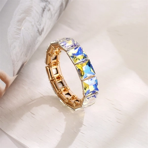Detail shot of a golden stretch bracelet featuring square-cut aurora crystals on paper