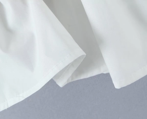 Gros plan sur la texture du tissu blanc avec coutures de qualité et détails de volant