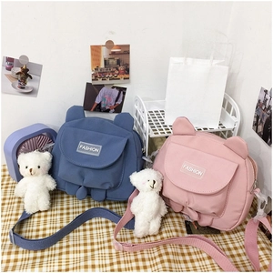 Detail of cute bear canvas messenger bags in blue and pink with fashion labels