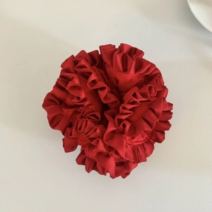 Detailed top view of a voluminous burgundy satin scrunchie with pleated ruffle edges