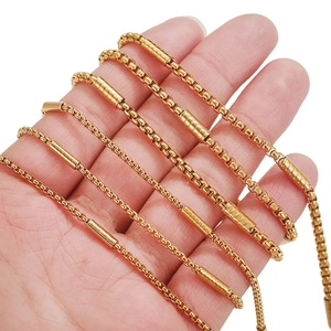 Golden round box chain necklace with cylindrical metal segments held by hand