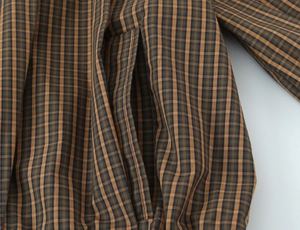 Macro shot of side pocket stitching on brown plaid cotton shirt with fine texture
