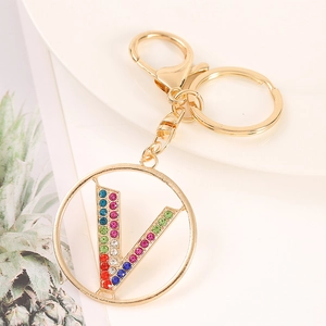Close-up of golden keychain with colorful rhinestone letter V pendant and alloy finish