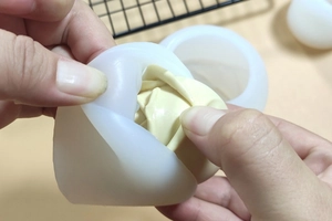 Detail showing the process of peeling a white silicone mold from a rose candle
