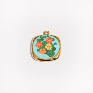 Vue macro détaillée du pendentif carré en or 18K avec émail bleu et motifs de fleurs orange