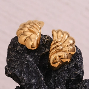 Detailed macro view of 18K gold plated half-round floral earrings on a black rock surface