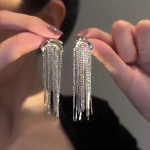 Close-up of long silver fringe tassel earrings with sparkling rhinestone studs