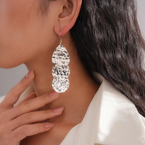 Gros plan de boucles d'oreilles triple goutte d'eau argentées avec texture martelée