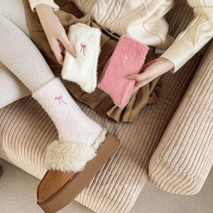 Detailed close-up of plush thermal socks with delicate bow embroidery in white and pink