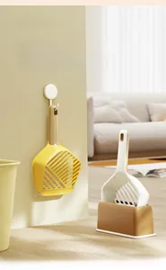 Detail view of wall-mounted yellow cat litter scoop and standing white shovel set