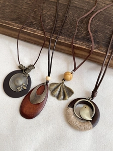 Detail of vintage wooden beads and leaf pendant necklaces on rustic fabric and wood
