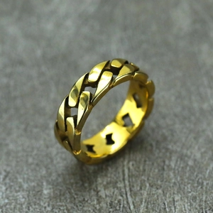 Close-up of golden Cuban link chain ring with high-gloss metallic finish on stone surface